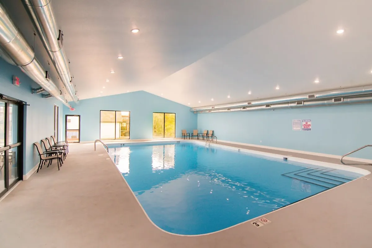 An inviting interior shot of the indoor swimming pool, featuring large windows that let in natural light and a comfortable seating area for guests to relax or socialize. The tranquil atmosphere makes it suitable for swimming year-round.
