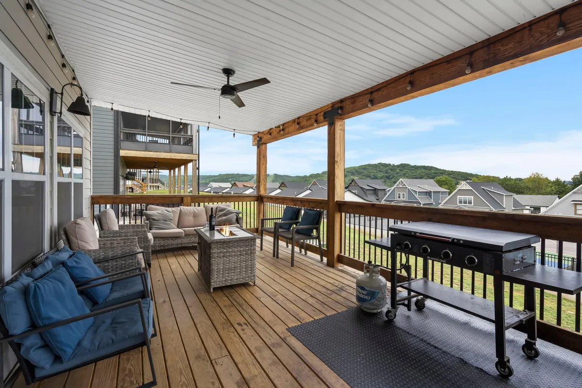 An exterior deck scene featuring comfortable seating, a grill, and a scenic view. The setting is perfect for outdoor dining, relaxing, or entertaining, with the backdrop of a beautiful sunset sky suggesting memorable evenings by the lake.