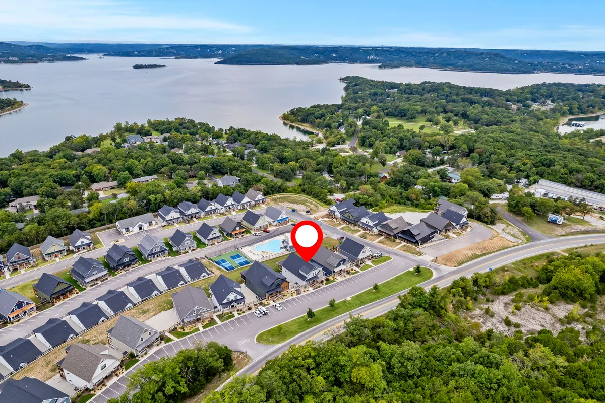 This exterior image presents a panoramic view of the community amenities, including the lake, the outdoor pool, residential buildings, and green spaces. Families and groups can be imagined swimming, boating, hiking, and gathering in communal areas. Soft evening lighting hints at the beauty of sunset views and alludes to the possibility of nature walks or lakeside relaxation in any season.