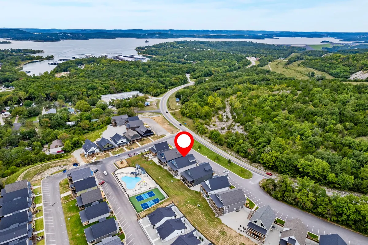A sweeping view captures lush greenery, a sparkling water body, a swimming pool, and a playground, all framed by residential buildings. The setting is serene and communal, evoking relaxation and shared outdoor experiences.